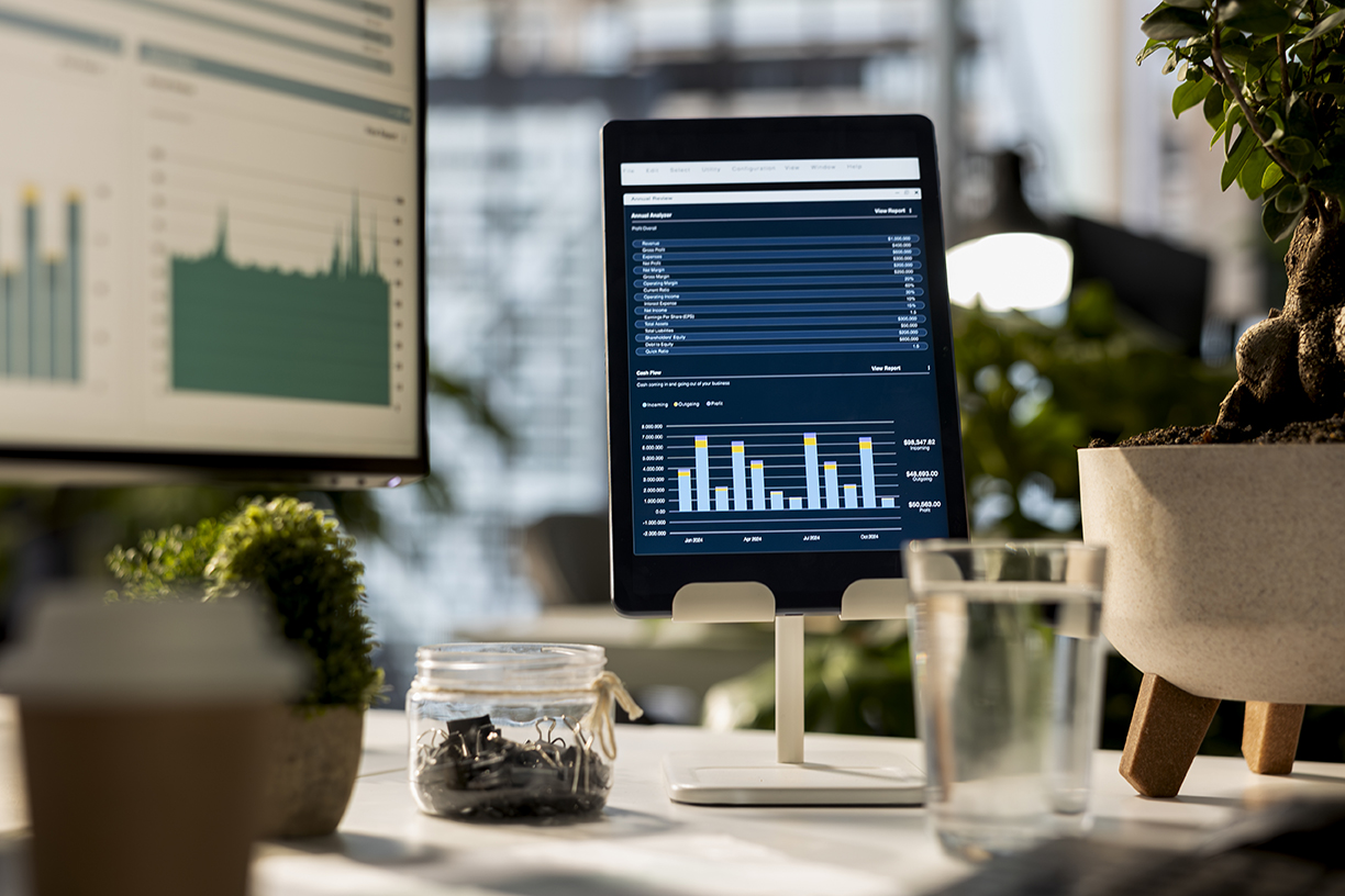 Tablet on a stand displaying business analytics dashboards on a tidy modern desk with plants